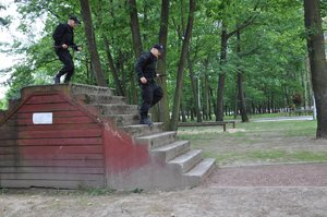 Policjanci podczas pokonywania toru przeszkód przebiegają przez skrzynię ze schodami