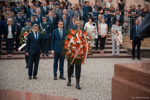 Od lewej: Wojewoda Śląski Jarosław Wieczorek, Prezes Rady Ministrów Mateusz Morawiecki, Marszałek Województwa Śląskiego Jakub Chełstowski składają wieniec przed Pomnikiem Józefa Piłsudskiego. W tle uczestnicy Wojewódzkich Obchodów Święta Policji w Katowicach