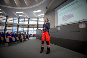 Zdjęcie kolorowe. Aula Komendy Wojewódzkiej Policji w Katowicach, do uczestniczek zwraca się jeden z prelegentów