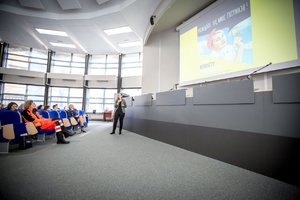 Zdjęcie kolorowe. Aula Komendy Wojewódzkiej Policji w Katowicach, do uczestniczek zwraca się jeden z prelegentów