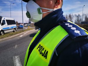 Zdjęcie kolorowe. Policjant w maseczce