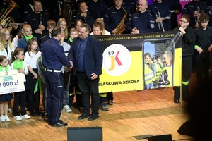 Policjant składa gratulacje przedstawicielom zwycięskiej szkoły