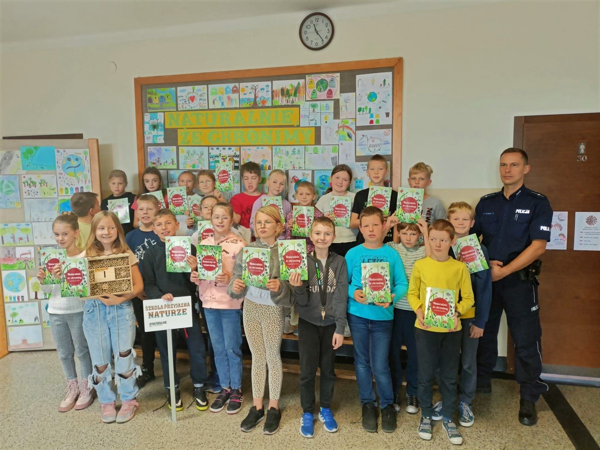 Zdjęcie kolorowe przedstawia grupę dzieci z policjantem.