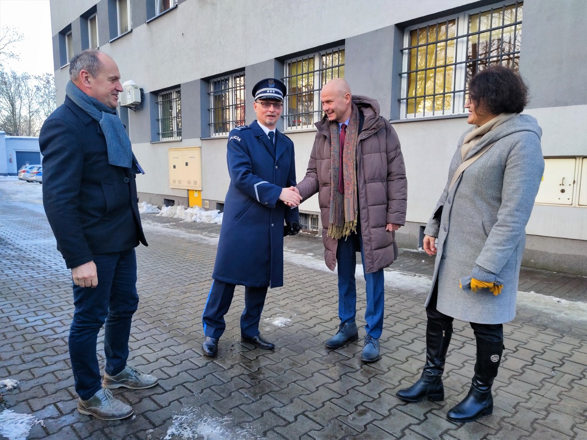 Zdjęcie przedstawia umundurowanego policjanta, który ściska dłoń mężczyzny stojącego obok. 