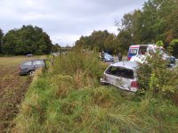 Fotografia przedstawia 2 pojazdy osobowe, które znajdują się w rowie. W tle widać ambulans oraz radiowóz policyjny