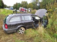 Fotografia przedstawia samochód skoda octavia w rowie. W tle widać wóz strażacki