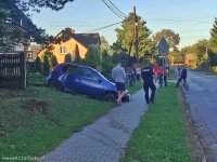 fotografia przedstawia niebieski samochód osobowy, który brał udział w zdarzeniu drogowym. Pojazd ten posiada uszkodzenia, znajduje się na skarpie, swoim przodem skierowany jest do jezdni.