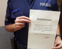 Policjant trzyma w ręku podziękowania o treści : Podziękowania dla Komendy Powiatowej Policji w Pszczynie a w szczególności dla ml.asp. Szymona Czysza za pomoc w organizacji udziału młodzieży i nauczycieli Zespołu Szkół Zawodowych i Ogólnokształcących w Woli w projekcie &quot; Przeciw mowie nienawiści&quot;