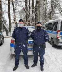 Fotografia przedstawia dwóch umundurowanych policjantów na tle radiowozu.