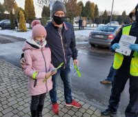 umundurowany policjant z dziewczynką i jej ojcem. Wszyscy posiadają opaski odblaskowe