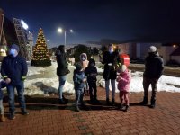 zmrok. Umundurowany policjant z grupą dzieci na parkingu. Wszyscy posiadają elementy odblaskowe