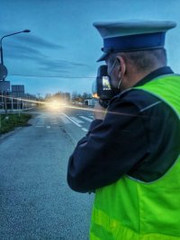 Zdjęcie kolorowe policjanta dokonującego pomiar prędkości