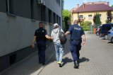 Zdjęcie kolorowe: dwóch policjantów prowadzi mężczyznę