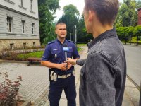 Zdjęcie kolorowe: policjant przed budynkiem starostwa udziela wywiadu przed kamerą