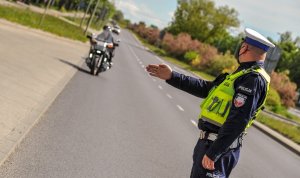 Zdjęcie kolorowe: policjant Ruchu Drogowego zatrzymuje do kontroli motocyklistę