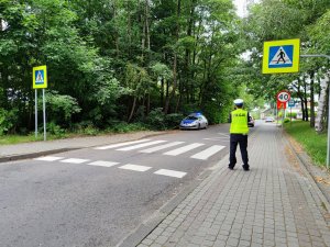 Zdjęcie kolorowe: policjant Ruchu Drogowego sprawdza poprawność oznakowania