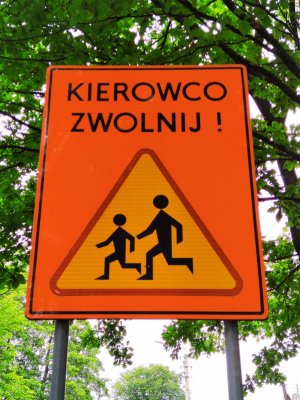 Zdjęcie kolorowe: znak drogowy napis Kierowco Zwolnij i znak przejścia dla pieszych