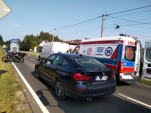 Zdjęcie kolorowe: na pierwszym planie nieoznakowany radiowóz, w tle motocykl, karetka pogotowia ratunkowego i bus