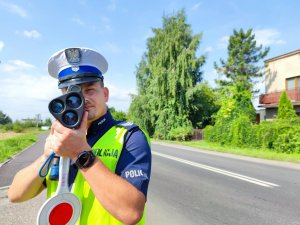 Zdjęcie kolorowe: policjant Ruchu Drogowego podczas pomiaru prędkości kierujących