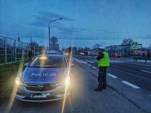 Zdjęcie kolorowe: policjant Ruchu Drogowego mierzy prędkość przejeżdżających pojazdów