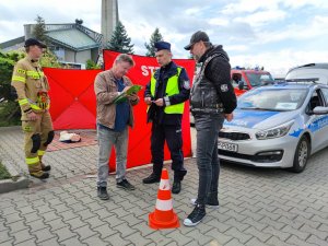 Zdjęcie kolorowe: mężczyzna, policjant i mężczyzna w stroju motocyklowym oraz strażak podczas obchodów Roadpol Safety Days