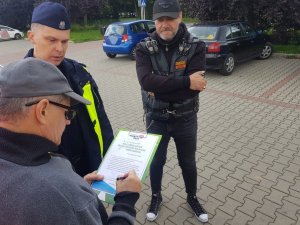 Zdjęcie kolorowe: mężczyzna wraz z policjantem i mężczyzną w stroju motocyklowym