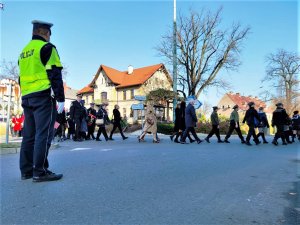 Zdjęcie kolorowe: umundurowany policjant ruchu drogowego podczas zabezpieczenia pochodu