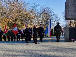 Zdjęcie kolorowe: kobieta przed mikrofonem, w tle widoczni uczestnicy zgromadzenia