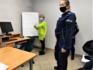 Zdjęcie kolorowe: na pierwszym planie widoczna policjantka, w tle uczestniczka spotkania robi zapiski