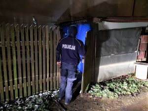 Zdjęcie kolorowe: umundurowany policjant przed wejściem do szopki