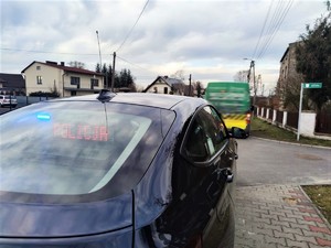 Zdjęcie kolorowe: widoczny nieoznakowany radiowóz, a w tle kontrolowany bus