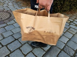 Zdjęcie kolorowe: papierowa torba, którą niesie umundurowany policjant