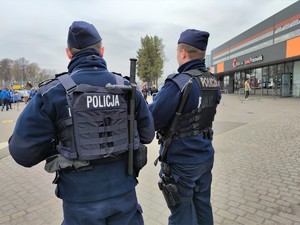 Zdjęcie kolorowe: dwóch umundurowanych policjantów, w tle widoczna kopalnia Pniówek