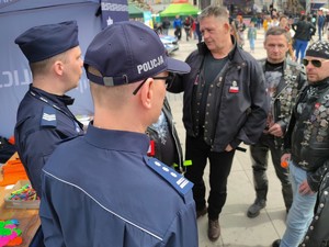 Zdjęcie kolorowe: dwóch umundurowanych policjantów podczas rozmowy z motocyklistami