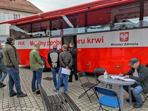 Zdjęcie kolorowe: krwiobus i osoby oczekujące na oddanie krwi.