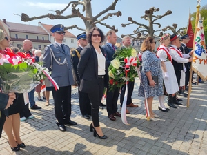 Zdjęcie kolorowe: widoczni uczestnicy obchodów wśród nich policjant w galowym mundurze