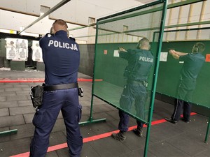 Zdjęcie kolorowe: trzech umundurowanych policjantów podczas ćwiczeń na strzelnicy