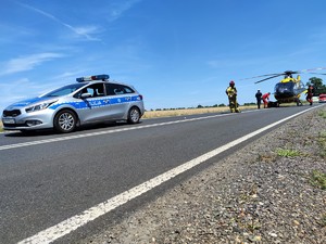 Zdjęcie kolorowe: oznakowany radiowóz policyjny i Lotnicze Pogotowie Ratunkowe.