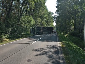 Zdjęcie kolorowe: wywrócony pojazd ciężarowy na drodze.