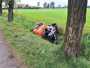 Zdjęcie kolorowe: wywrócony walec drogowy leżący w rowie.