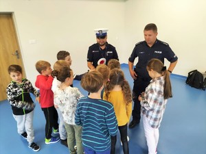 Zdjęcie kolorowe przedstawia grupkę dzieci obok umundurowanych policjantów.