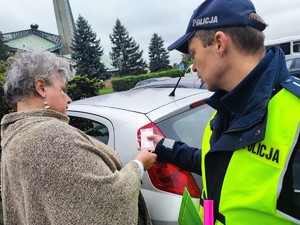 Zdjęcie kolorowe przedstawia umundurowanego policjanta wraz z kobietą podczas rozmowy.