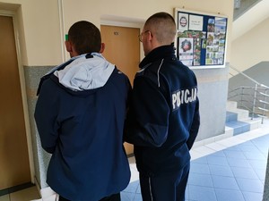 Zdjęcie kolorowe przedstawia umundurowanego policjanta z zatrzymanym mężczyzną