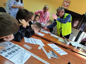 Zdjęcie kolorowe przedstawia policjanta, który trzyma szybę na której dziecko odbija swoją dłoń.