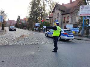 Zdjęcie kolorowe przedstawia policjanta który kieruje ruchem.