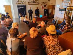 Zdjęcie kolorowe przedstawia 3 umundurowanych policjantów przed grupą seniorów.