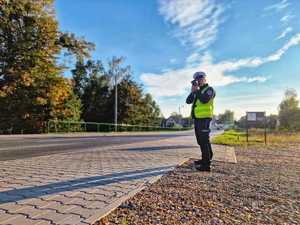 Zdjęcie przedstawia policjanta który mierzy prędkość pojazdów.