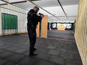 Zdjęcie przedstawia umundurowanego policjanta podczas ćwiczeń strzeleckich z broni maszynowej.