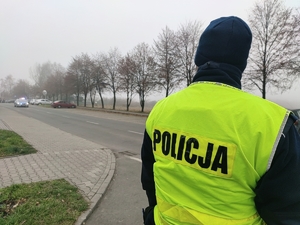 Zdjęcie przedstawia z przodu policjanta, z tyłu maszerujący tłum.