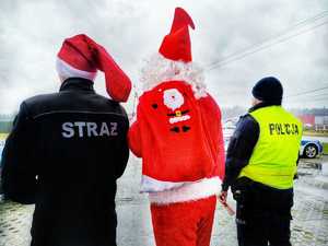 Zdjęcie przedstawia strażaka, Mikołaja i policjanta, którzy stoją tyłem.